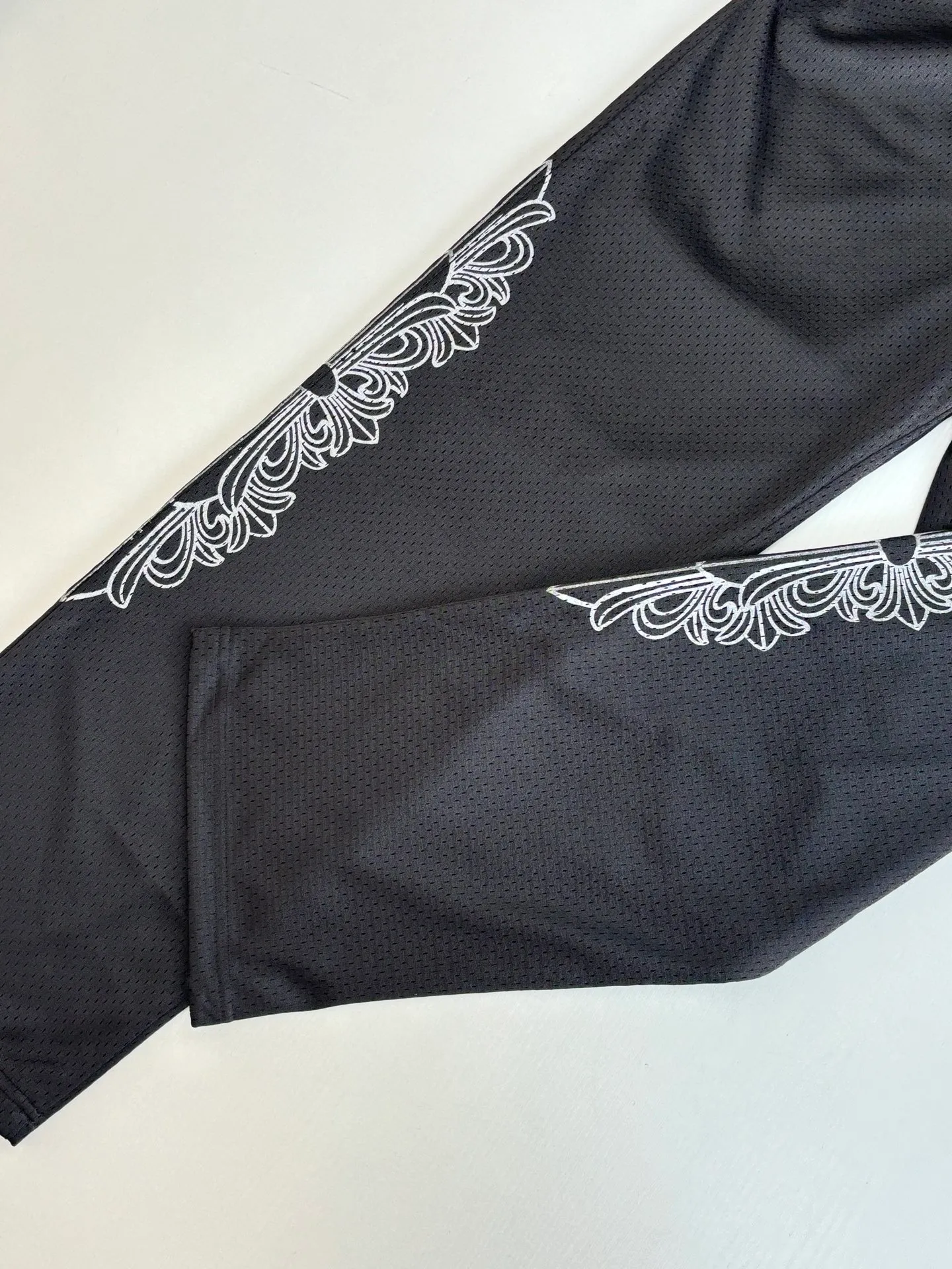 P340 Chrome Heart*/Chrome Heart Sanskrit mesh ice hockey suit straight trousers. The original version was purchased for 15,989 and developed. The fabric is made of custom weaving and dyeing technology. It is made of selected black mesh fabric, showing a unique sports style. The fabric has been specially treated to provide excellent breathability and comfort while maintaining a crisp and structured look. The double-layer design structure enhances the overall texture and makes the wearing experience more three-dimensional and full. The brand's iconic patterns are printed in many places, and high-precision printing technology is used to ensure that the patterns are clear and sharp. The silver printing has a glitter effect, showing charming luster changes under different lights. All printings undergo strict color difference control to ensure accurate color reproduction. The silver-plated pattern design on the sleeve arms is particularly eye-catching, showing the brand's consistent dark luxury style. In terms of details, the latest custom-woven labels are used, and the workmanship is exquisite. The overall shape is designed for both men and women, with both fashion and practicality. This T-shirt perfectly combines sports elements with high fashion craftsmanship, making it the brand's iconic street style item.  Size：S/M/L